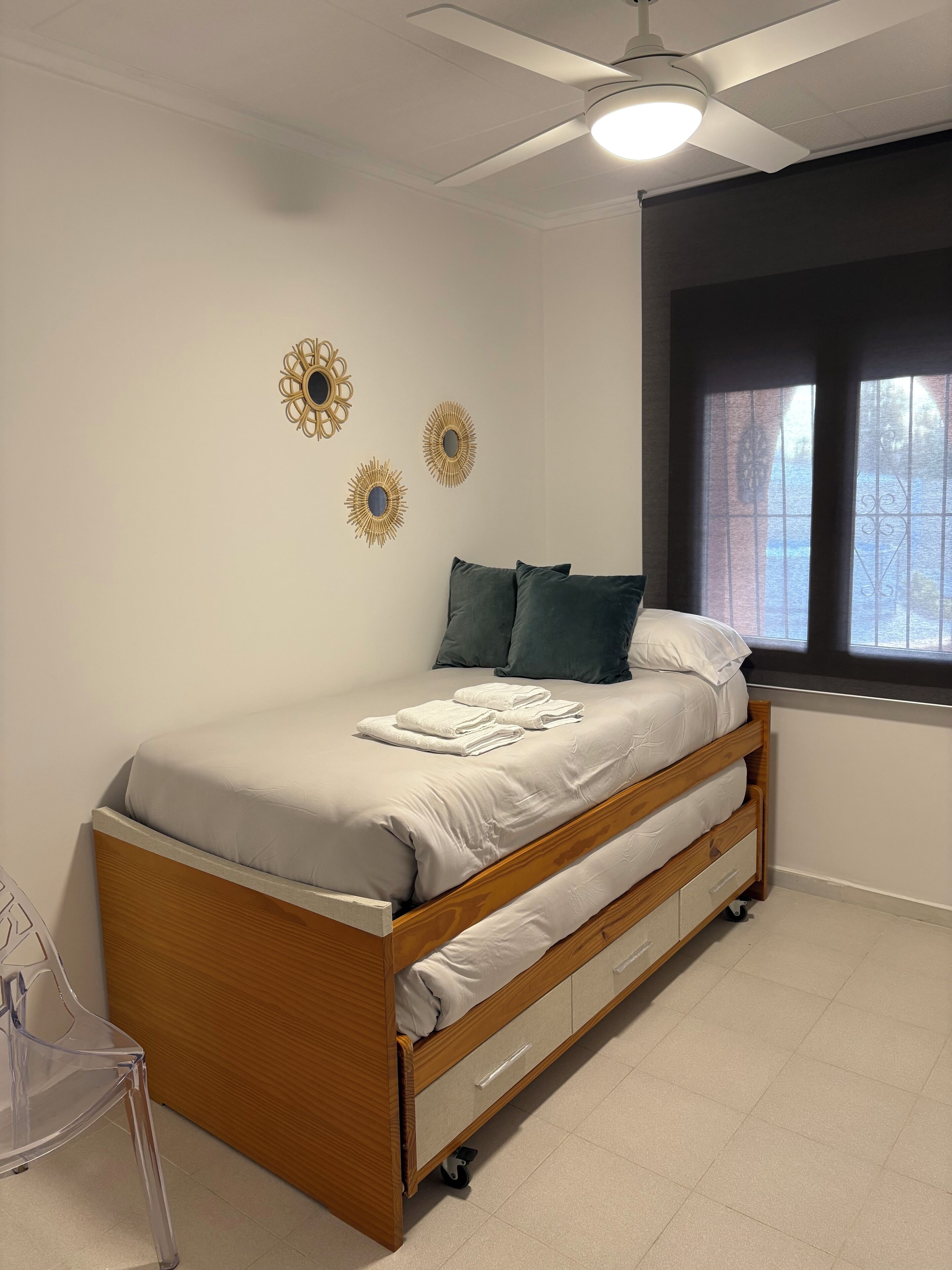 A bedroom with a wooden bed, a ceiling fan, and decorative wall mirrors.