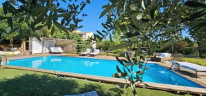 A rectangular swimming pool with a wooden deck, surrounded by lounge chairs and a covered seating area. - La Bastide des Oliviers Provencal gîte with swimming pool in 1 ha of greenery (Carpentras)
