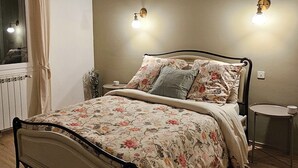 A bedroom with a bed, a chandelier, a nightstand, and a window with curtains.