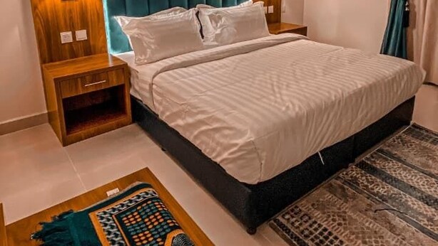 Une chambre d’hôtel moderne avec un grand lit, deux tables de chevet, un appareil de climatisation et un tapis à motifs.