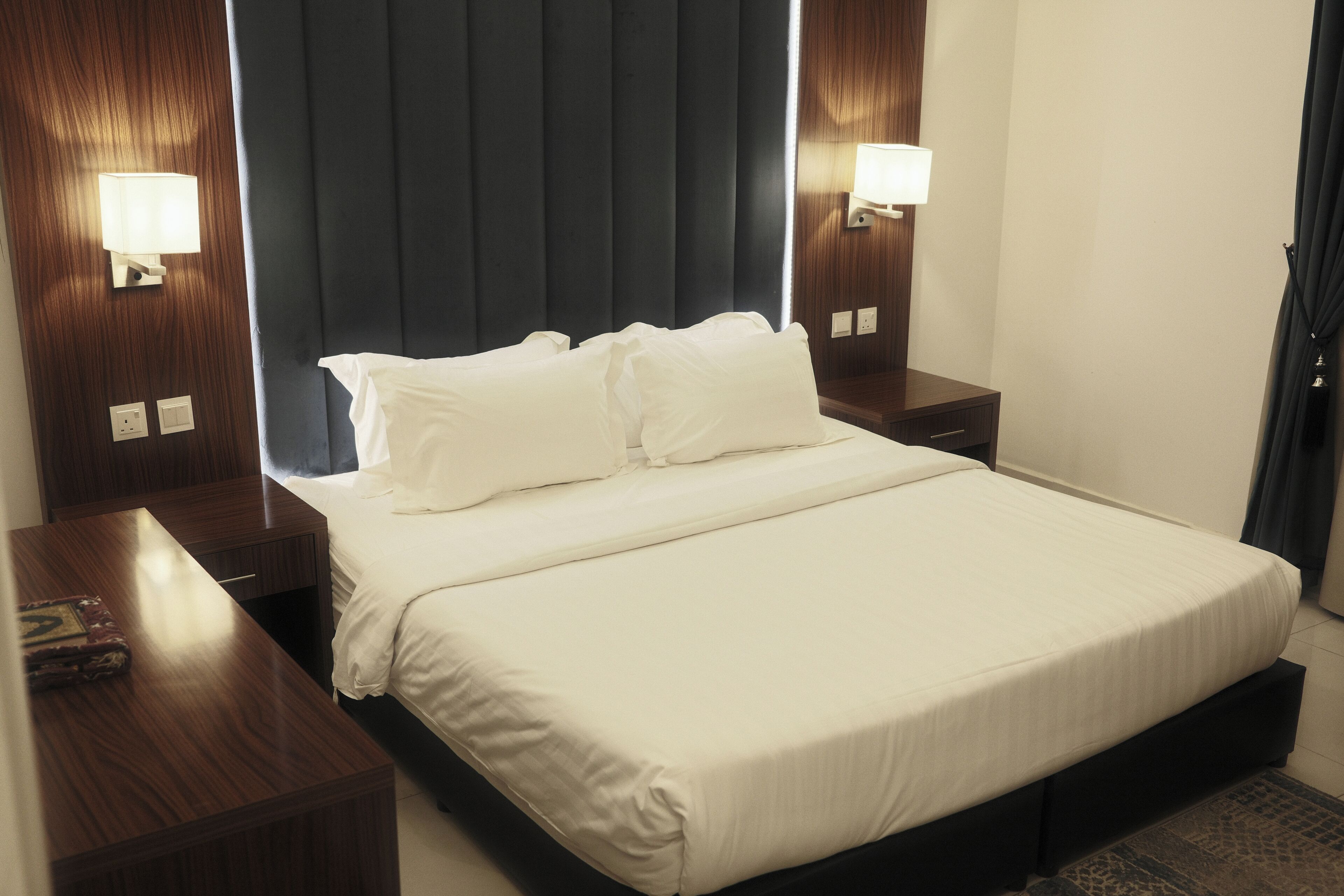 Ein Hotelzimmer mit einem großen Bett, zwei Nachttischen und zwei Wandleuchten.