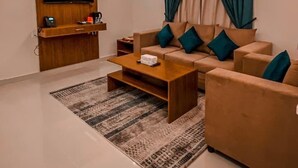 Un salon moderne avec un canapé, une table basse, un téléviseur et des rideaux.