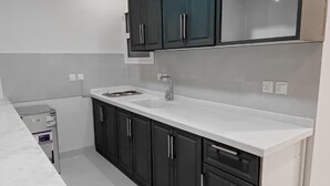 Une cuisine moderne avec des meubles de couleur sombre, un plan de travail blanc et un lave-vaisselle encastré.