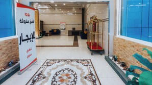 Un hall d’hôtel avec un tapis à motifs, un comptoir d’accueil et un plafond décoratif.