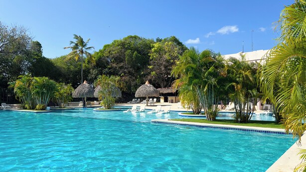 A clear blue swimming pool surrounded by lounge chairs and palm trees. - Discover Coronado's Best Area with Pool (Panamá Oeste Province)