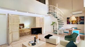 A spacious living area with a large TV, a sofa, a coffee table, and a staircase leading to an upper level. - Discover Coronado's Best Area with Pool (Panamá Oeste Province)