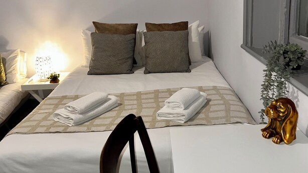 Une chambre d’hôtel avec un lit, deux oreillers, une table de chevet avec une lampe, une chaise, une fenêtre et une œuvre d’art représentant un zèbre accrochée au mur.