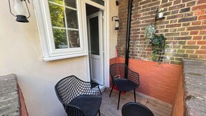A small outdoor seating area with two black chairs and a wooden deck. - Stylish apt in a 1938 building w/parking (London)