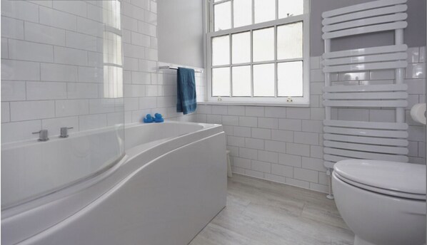 Bathroom features a bathtub, toilet, and towel rack.