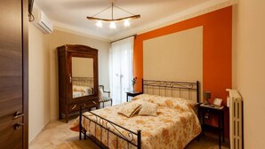 Een slaapkamer met een bed, een houten garderobe, een bureau met lamp en een radiator.