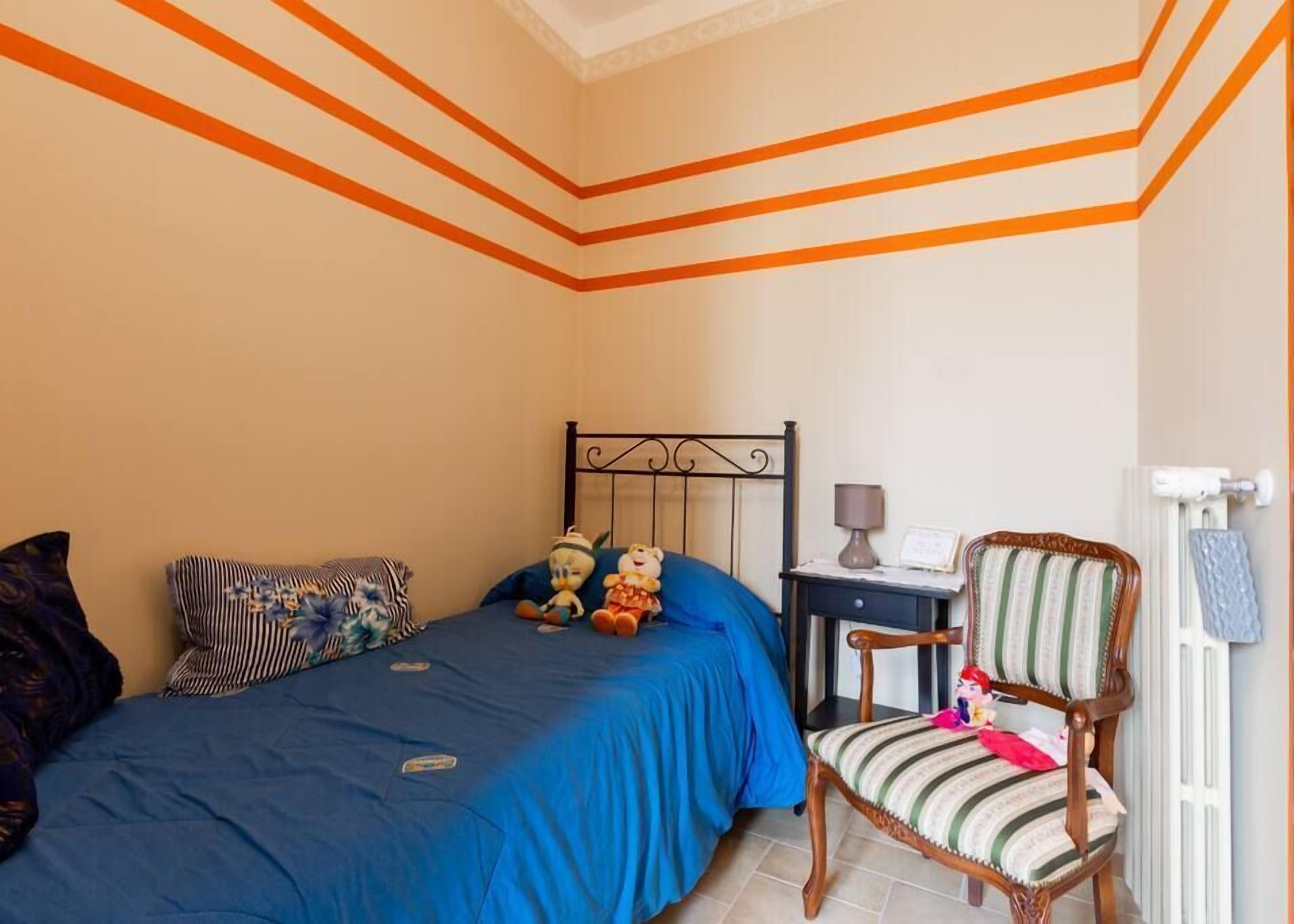 A bedroom with a bed, a chair, a nightstand, and a radiator.