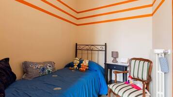 A bedroom with a bed, a chair, a nightstand, and a radiator.