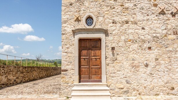 Un bâtiment en pierre doté d’une grande porte en bois et d’une petite fenêtre située au-dessus.