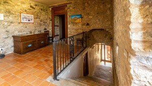 Une pièce rustique aux murs de pierre, dotée d’un escalier en bois et d’une rambarde en métal.