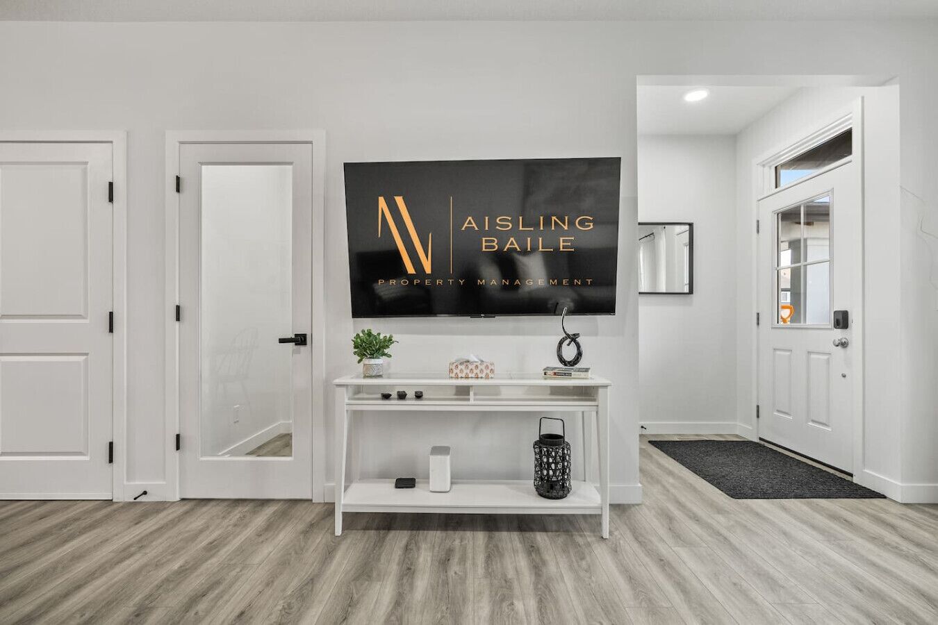 Un pasillo moderno con un televisor montado mostrando 'AISLING BAILE PROPERTY MANAGEMENT'.