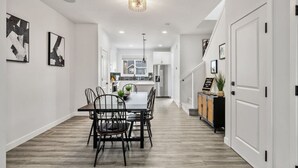 Una cocina moderna con armarios blancos, una isla central y una zona de comedor con mesa y sillas.