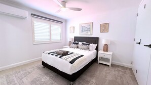 A bedroom with a bed, bedside tables, a ceiling fan, and a door.