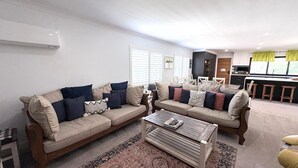 A living room with two sofas, a coffee table, and a kitchen in the background.