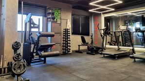 A modern gym with various exercise equipment, including weight machines, a bench press, and cardio machines. - Lindo Estúdio com Jacuzzi, Sauna e Coworking (Maceió)