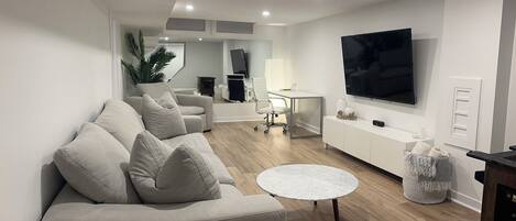 A modern living room with a sofa, a coffee table, and a TV mounted on the wall.