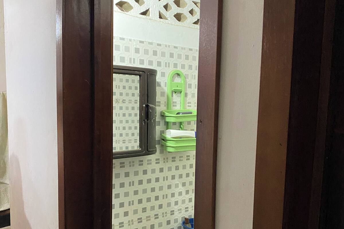 A bathroom with a toilet, sink, and a green cleaning cart.