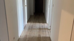 Un couloir étroit avec un plancher en bois et des murs blancs.