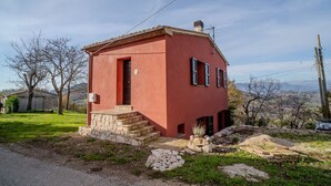Une petite maison rouge, de plain-pied, avec un escalier en pierre menant à l’entrée.