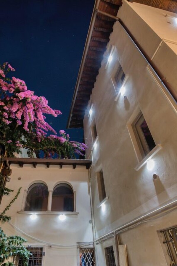 A building with arched windows and a balcony with pink flowers.