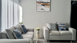 A modern living room with two sofas, a vase with flowers, and a painting on the wall. - Hidden River Lodge (La Fortuna)
