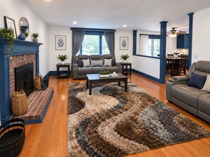 Un salon avec une cheminée, un ensemble de canapés, une table basse et un tapis.