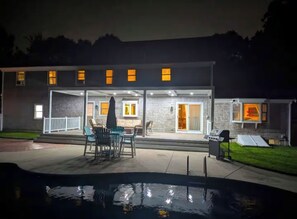 Une maison moderne dotée d’un patio couvert, d’un espace salon extérieur et d’une piscine.