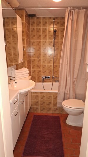 Une salle de bain équipée d’une baignoire, de toilettes, d’un lavabo et d’un rideau de douche.