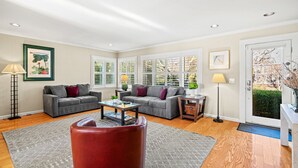 Ein Wohnzimmer mit zwei grauen Sofas, einem Couchtisch, einem roten Sessel und einem Beistelltisch mit einer Lampe.