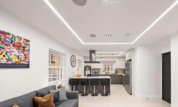 A modern kitchen with a central island, bar stools, and a large window. - Fatherson Road, Reading (Berkshire)