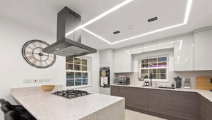 Une cuisine moderne dotée d’un îlot central, d’appareils électroménagers intégrés et d’une grande horloge murale.