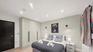 Une chambre à coucher moderne, avec un lit, des tables de chevet, une armoire et une porte.