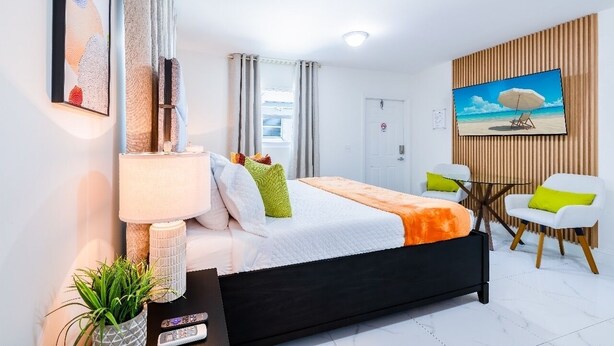 Een moderne hotelkamer met een bed, bureau, stoel, televisie en een schilderij aan de muur.