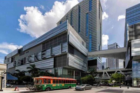 A modern building with a glass facade and a green bus in front.
