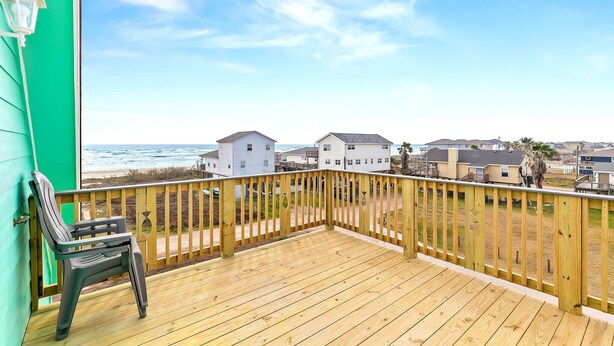 Une terrasse en bois offrant une vue sur l’océan et les maisons de plage.