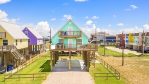 Une propriété colorée située en bord de mer, avec une maison principale dotée d’un balcon, entourée d’autres maisons aux couleurs vives.