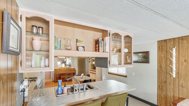 Een kleine keuken met een geïntegreerd barretje, houten kastjes, en een eethoek met een tafel en stoelen.