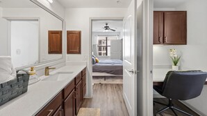 A modern bathroom with a large mirror, wooden cabinets, and a white countertop.