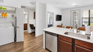 A modern kitchen with a dishwasher, wooden cabinets, a white countertop, and a built-in sink.