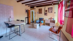 A dining area with a table and chairs, a sofa, a small cabinet, and a red curtain. - Casa Daniele - Savigno (Savigno)