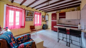 A room with a bed, a chair, a small table, a kitchenette, and a window with curtains. - Casa Daniele - Savigno (Savigno)