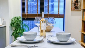 A dining table set with white plates, bowls, a wine bottle, and glasses. - Northern Qtr Corner Flat With Balcony & City Views - Pass the Keys (Manchester)
