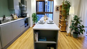 A modern kitchen with a central island, built-in appliances, and a wooden floor. - Northern Qtr Corner Flat With Balcony & City Views - Pass the Keys (Manchester)