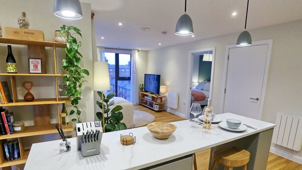 A modern kitchen with a central island, wooden bar stools, and pendant lighting. - Northern Qtr Corner Flat With Balcony & City Views - Pass the Keys (Manchester)