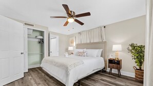 A bedroom with a bed, a ceiling fan, a nightstand with a lamp, a potted plant, and a closet with hanging clothes. - Near USF, Ybor City, Busch Gardens/RayJ Stadium + TV Backyard  & Games, Slps 8! (Tampa)