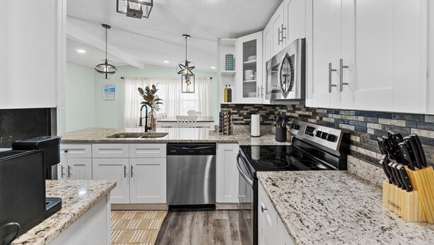 A modern kitchen with white cabinets, granite countertops, stainless steel appliances, and pendant lighting. - Near USF, Ybor City, Busch Gardens/RayJ Stadium + TV Backyard  & Games, Slps 8! (Tampa)